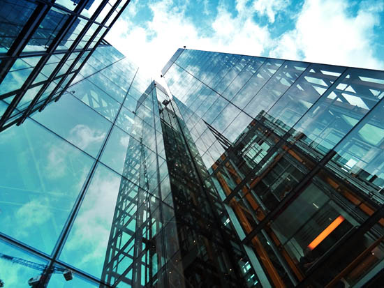 Photograph looking upwards at glass buildings and the sky