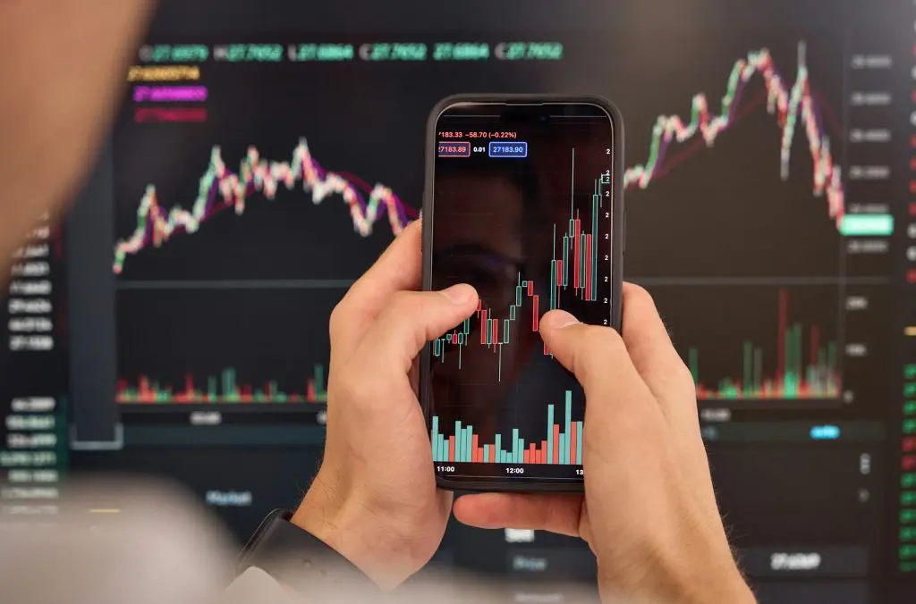 Investor trader analyzing crypto stock trade invest mobile market. Over shoulder