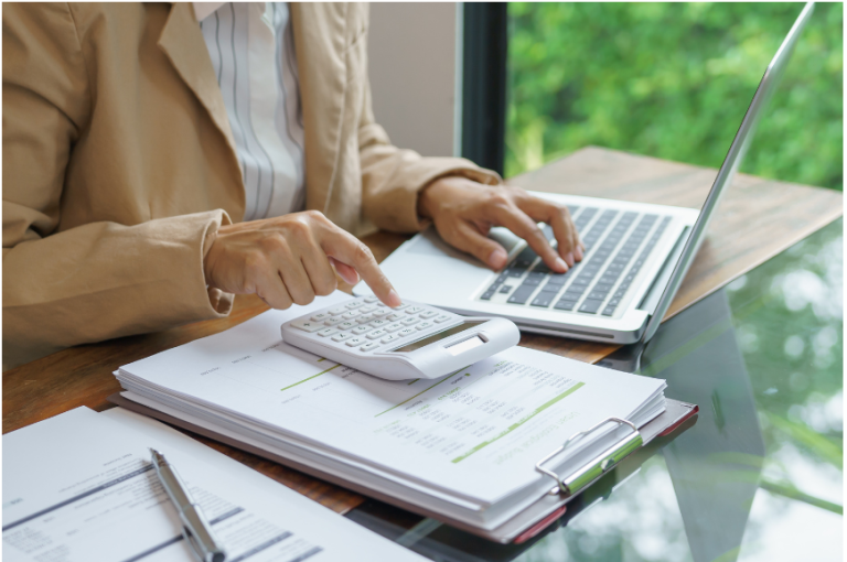 A person using a calculator and laptop to budget